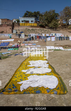 Wäscheservice Tag auf dem Ganges, Varanasi, Uttar Pradesh, Indien. Kleidung und Bettwäsche sind im Fluss und verteilen sich auf die Bank des Flusses zu trocknen Waschen Stockfoto