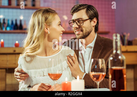 Lächelnd Mann in Brillen und Jacke, die Freundin am Tisch mit Kerzen in Restaurant Stockfoto