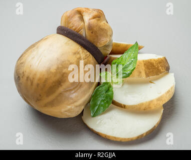 Traditionelle italienische geräuchert Scamorza Käse mit Kräutern auf grauem Hintergrund. Stockfoto