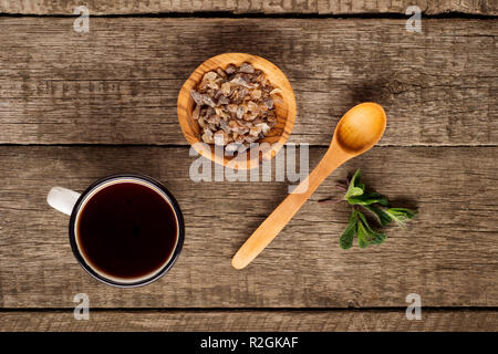 Tasse Tee mit Minze Blatt und braunen Zucker in die Schüssel auf rustikalen Holzmöbeln Hintergrund. Kopieren Sie Platz. Ansicht von oben Stockfoto