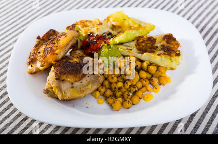 Appetitlich gebratene Hühnerkeule mit panierten Kohlblätter und gedünstetem Kichererbsen mit Guacamole und Tomatensauce. Stockfoto
