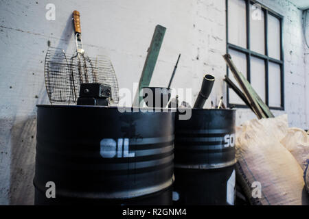 Alte Fässer öl Schwarz auf Weiß grunge brick Hintergrund in einer Garage. Stockfoto