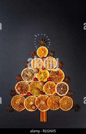 Weihnachtsbaum aus getrockneten Orangen, Zimt und Sternanis auf dunklem Hintergrund. Von oben gesehen. Stockfoto