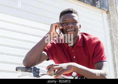 Teenager Jungen auf Fahrrad Gespräch am Handy im Freien Stockfoto