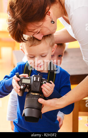 Glückliche Kindheit. Mutter und ihre Kinder jungen Kinder spielen mit Kamera, Bild zu Hause. Real Photo Stockfoto