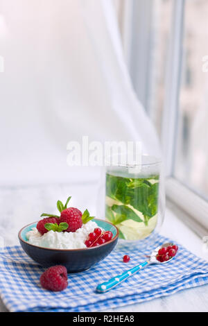 Tee mit Minze im Glas und Müsli zum Frühstück auf den Tisch am Fenster. Gute Frühling Morgen Stockfoto