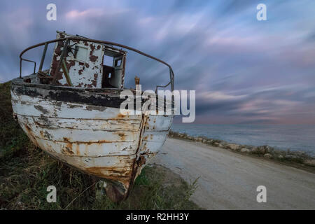 Ein verlassenes altes, hölzernes Fischerboot am Strand mit super Sky Stockfoto