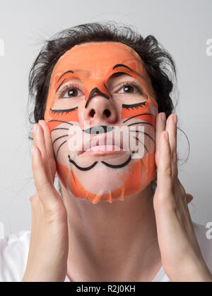 Beauty Spa portrait einer jungen brünette Frau mit einem Fuchs Gewebe Maske auf Gesicht, weißen Hintergrund. Stockfoto