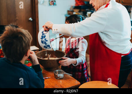 Zwei Kinder ihrer Großmutter einen Kuchen backen zu helfen Stockfoto