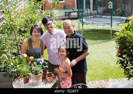 Porträt Lächeln multi-Generation, Familie, Gartenarbeit, verguss Blumen im sonnigen Hof Stockfoto