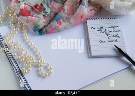 Coco Chanel Zitate auf einen Block Notiz geschrieben, pearl Zubehör und und seidig Blume Shirt, Inspiration phrase" Die mutigen Akt ist noch mit Thi Stockfoto