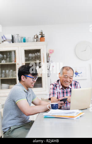 Sohn helfen älteren Vater Rechnungen bezahlen am Laptop Stockfoto