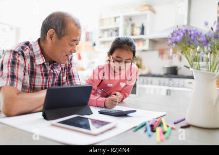 Großvater und Enkelin Färbung und Verwendung digitaler Tablet in der Küche Stockfoto