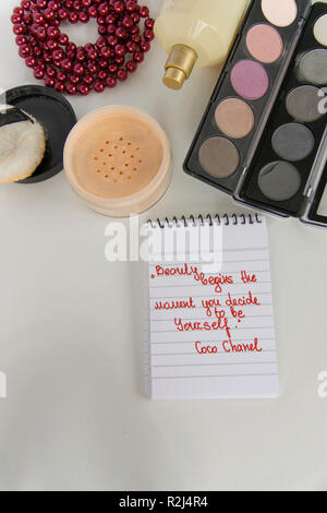 Coco Chanel Zitate auf einen Block Notiz geschrieben, pearl Zubehör und bis auf weißem Hintergrund machen, inspiration Satz "Schönheit beginnt in dem Moment, in dem Sie entscheiden Stockfoto