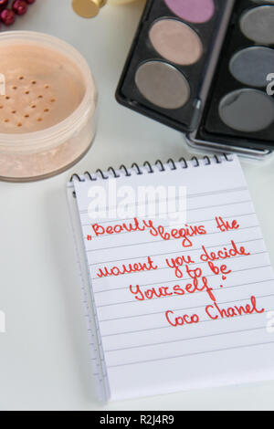 Coco Chanel Zitate auf einen Block Notiz geschrieben, pearl Zubehör und bis auf weißem Hintergrund machen, inspiration Satz "Schönheit beginnt in dem Moment, in dem Sie entscheiden Stockfoto