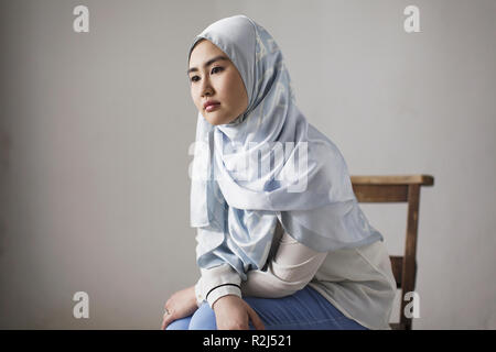 Nachdenkliche junge Frau in blauer Seide hijab Stockfoto