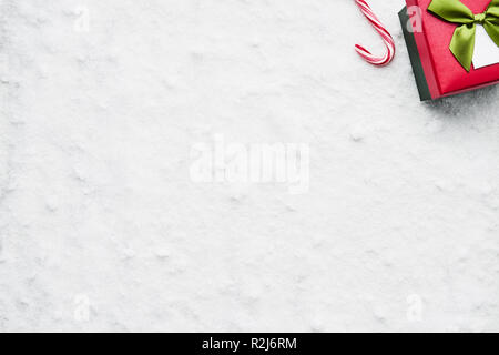 Blick von oben auf die grüne und rote Weihnachten Geschenkbox mit Schleife und Candy Cane auf dem Schnee. Kopieren Sie Platz für Text. Stockfoto
