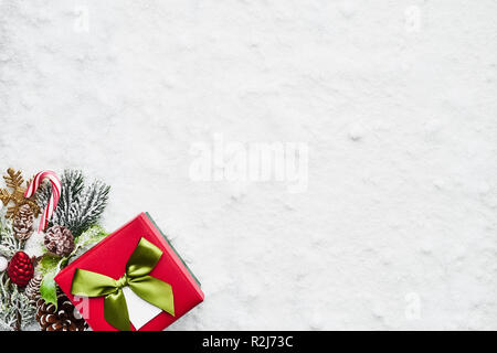 Blick von oben auf die grüne und rote Weihnachten Geschenkbox mit Schleife und Deko auf dem Schnee. Kopieren Sie Platz für Text. Stockfoto