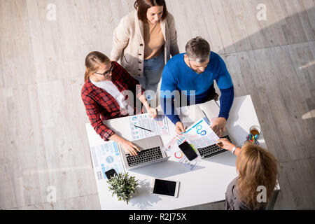 Kreatives Team von Marketing Profis arbeiten mit Diagrammen in modernen Büro: Sekretärin, Papier an die Kolleginnen und Kollegen über das Projekt Brainstorming Stockfoto