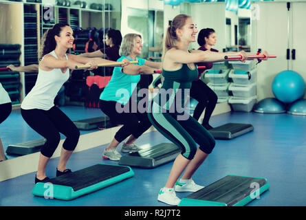 Freundliche Frauen arbeiten auf Aerobic Step Plattform im modernen Fitnessraum Stockfoto