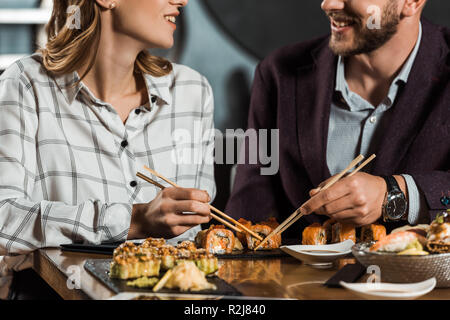 Teilweise mit Blick auf die lächelnde Paar Sushi essen im Restaurant Stockfoto
