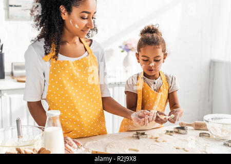 Zuversichtlich afrikanischen amerikanischen Mutter und Tochter cookies Vorbereitung mit Formen in der Küche Stockfoto