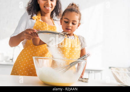 Zugeschnittenes Bild des afrikanischen amerikanischen Mutter und Tochter Teig vorbereiten und Sieben Mehl in der Küche Stockfoto