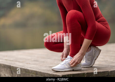 Nahaufnahme eines weiblichen Jogger schnüren ihre Schuhe vor der Ausführung Stockfoto