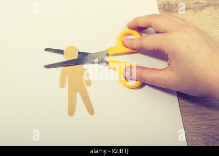 Schere schneiden das Papier Mann auf weißem Papier auf Holz- Hintergrund Stockfoto