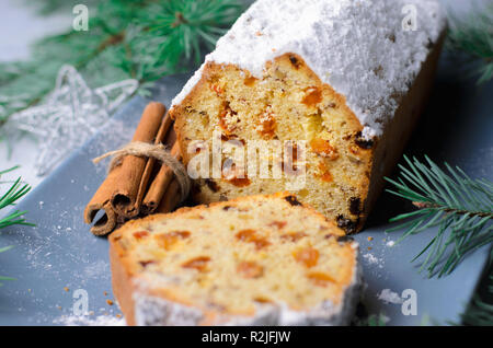 Obst und Mutter Brot Kuchen mit Puderzucker bestäubt, Weihnachten und Winter Urlaub gönnen, hausgemachte Kuchen mit Rosinen auf grauem Hintergrund Stockfoto