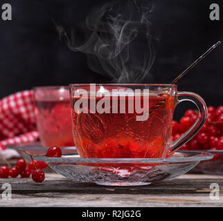 Frischem heißem Kaffee von viburnum Beeren in eine transparente Schale auf einem grauen Hintergrund Holz Stockfoto