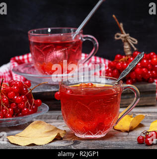 Frischem heißem Kaffee von viburnum Beeren in eine transparente Schale auf einem grauen Hintergrund Holz Stockfoto