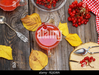 Transparente Tasse mit heißem Tee aus viburnum frische Beeren Beeren auf einem grauen Holz- Tabelle, Ansicht von oben Stockfoto