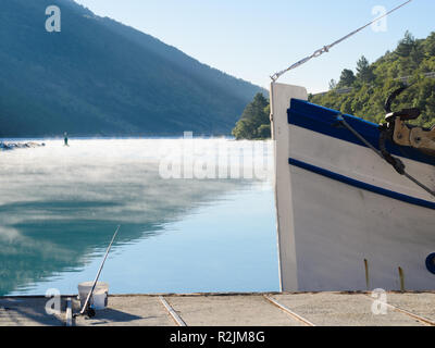 Kleines Fischerboot Bogen mit Morgennebel auf dem Meer in einem Abstand angedockt Stockfoto