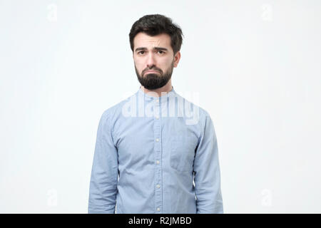 Kerl suchen unzufrieden und müde. Der Mensch ist unglücklich und denkt an etwas Spaß beim Arbeiten Stockfoto