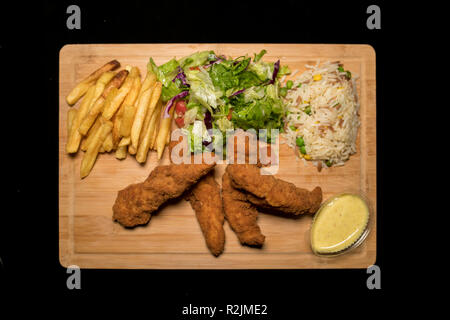 Huhn Hühnerfiletstreifen serviert mit Reis, Salat und französischen Freunden auf Holz Stockfoto