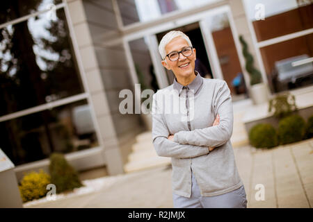 Outdoor Portrait von Happy fröhlich senior Geschäftsfrau mit verschränkten Armen Stockfoto
