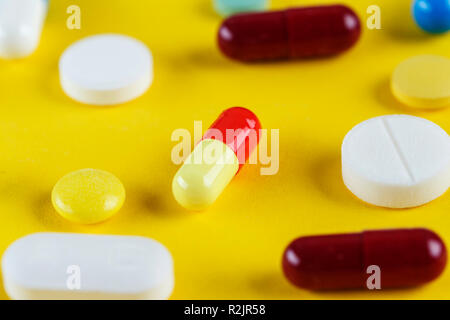 Verschiedene Tabletten und Kapseln auf gelbem Hintergrund verstreut, Platz für Text Stockfoto