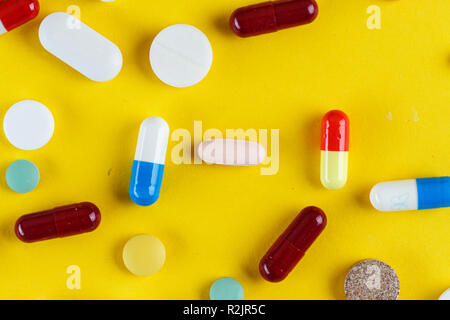 Verschiedene Tabletten und Kapseln auf gelbem Hintergrund verstreut, Platz für Text Stockfoto