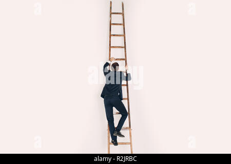 Ein Mann im schwarzen Anzug klettert die Treppe hoch. Karriere und das Wachstum in der Wirtschaft Konzept. Stockfoto