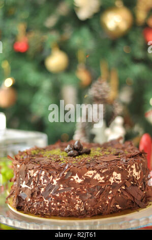 Köstliche frische Schokolade Pistaccio Kuchen mit Schokolade Stück um und Pistazien auf oben auf Glasplatten serviert mit Weihnachten Dekoration Stockfoto