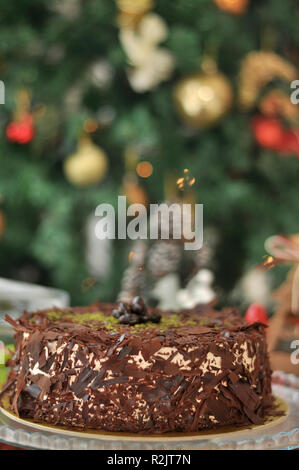 Köstliche frische Schokolade Pistaccio Kuchen mit Schokolade Stück um und Pistazien auf oben auf Glasplatten serviert mit Weihnachten Dekoration Stockfoto