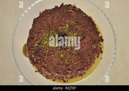 Köstliche frische Schokolade Pistaccio Kuchen mit Schokolade Stück um und Pistazien auf oben auf Glasplatten serviert mit Weihnachten Dekoration Stockfoto