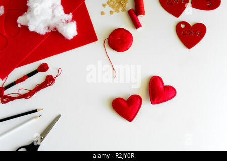 Valentinstag Filz Kunsthandwerk. Frau Hände nähen roten Herzen. DIY. Flach. Ansicht von oben Stockfoto