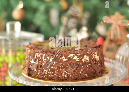 Köstliche frische Schokolade Pistaccio Kuchen mit Schokolade Stück um und Pistazien auf oben auf Glasplatten serviert mit Weihnachten Dekoration Stockfoto