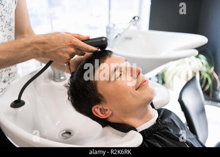 Mann Friseur waschen Kopf einer stattlichen lächelnd Client Stockfoto