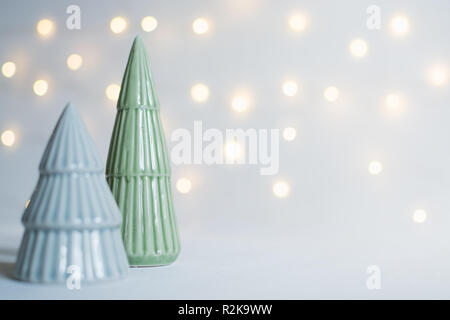 Keramik Spielzeug Weihnachtsbaum Statuetten mit Girlande bokeh auf Hintergrund, geringe Tiefenschärfe. Stockfoto
