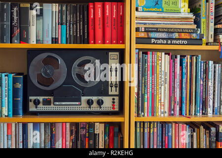 Vintage reel-to-reel Magnetband audio Recorder in der Bibliothek voller bunter Bücher Stockfoto