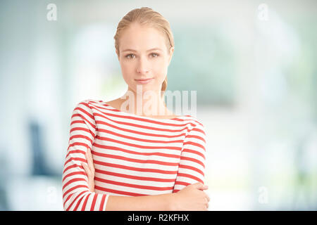 Porträt der attraktive junge blonde Frau mit gestreiften Hemd während Kamera suchen und lächelnd. Stockfoto