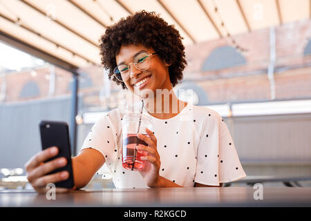 Junge blogger Fotos machen für soziale Medien, sitzen im Café im Freien Stockfoto